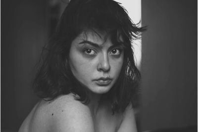 Portrait of young woman against black background