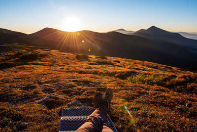 Low section of person on mountain against sky