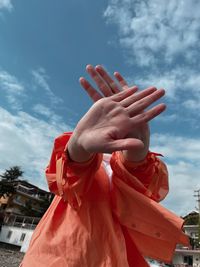 Low angle view of woman holding hands against sky