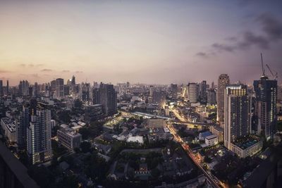 Aerial view of city lit up against sky