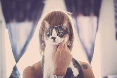 Woman covering face with cat at home