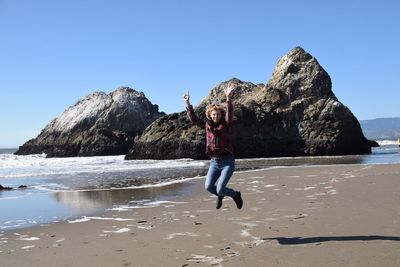 Portrait of young woman on beach against clear blue sky