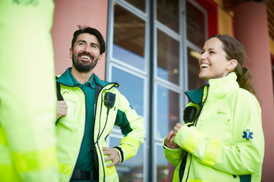 Smiling paramedics talking while standing outside hospital