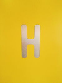 Close-up of arrow symbol against yellow background