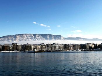 Scenic view of sea by buildings against blue sky