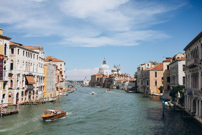 Canal amidst buildings in city against sky