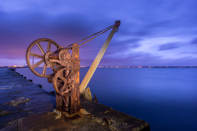 Ferris wheel by sea against blue sky