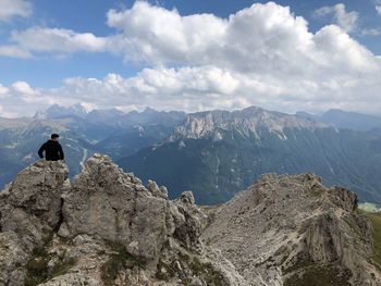 Rear view of people on rock by mountains against sky