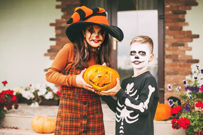 Brother and sister celebrate halloween on the street near the house in costumes and make-up