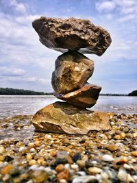 Close-up of pebbles in sea against sky