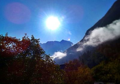 Sun shining through clouds over mountains