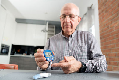 Low angle view of senior man holding glaucometer