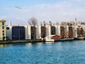 Buildings by river against sky in city