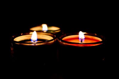 Close-up of lit tea light candles in the dark