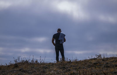 Rear view of adult man against cloudy sky and sea