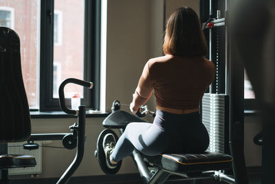 Young fitness brunette woman training for hand and leg muscles equipment at the gym