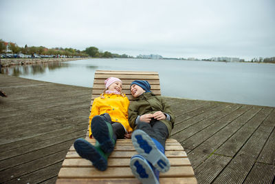 Brother an sister relaxing on chair by lake