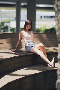 Full length portrait of woman sitting outdoors