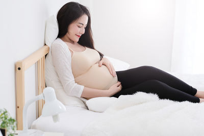 Young woman sitting on bed at home