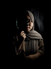 Portrait of young woman holing leaf in darkroom