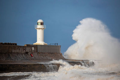 Lighthouse by sea against sky