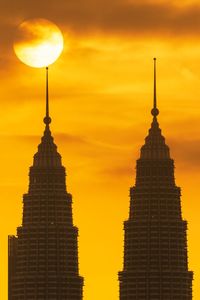 Low angle view of buildings against orange sky