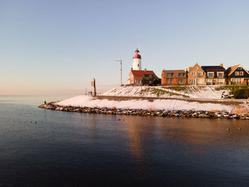 View of lighthouse by sea against clear sky