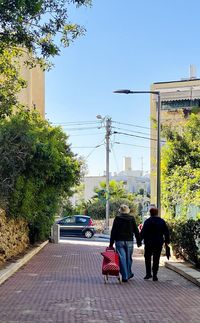 Rear view of women walking on street in city