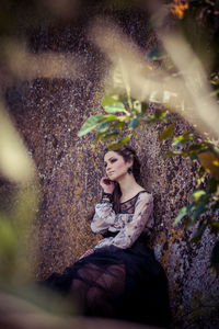 Young woman looking away while sitting on tree