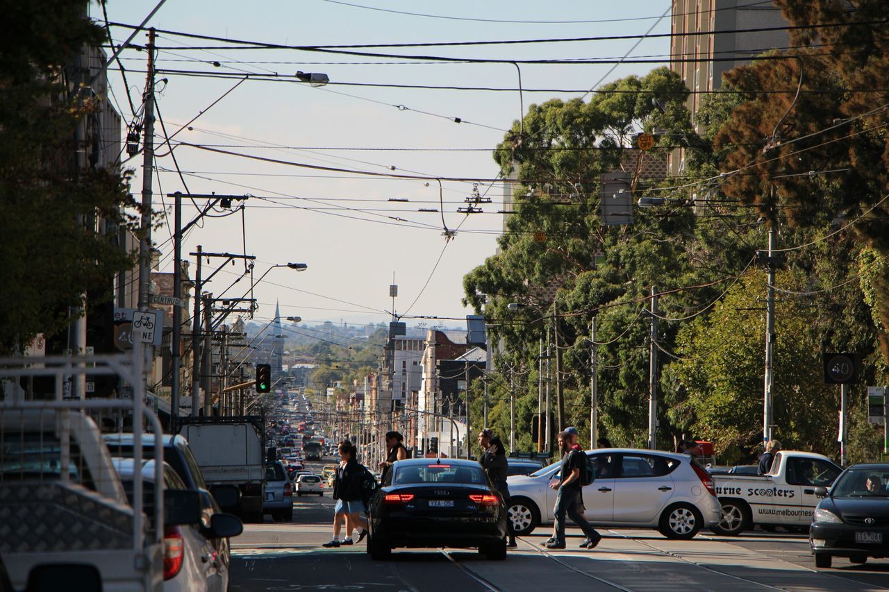 car, transportation, land vehicle, mode of transport, street, building exterior, architecture, road, built structure, city, tree, traffic, on the move, city life, city street, power line, incidental people, travel, the way forward, day