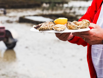 Midsection of man holding ice cream on beach