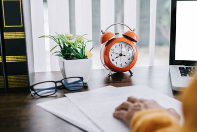 Man walking by laptop with alarm clock on table at home