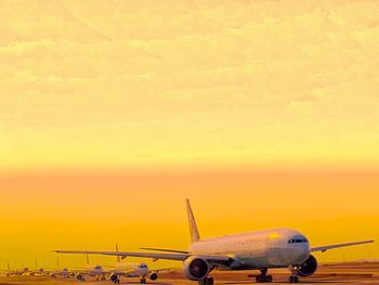 Airplane on runway against sky during sunset