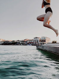 Man jumping over sea against clear sky