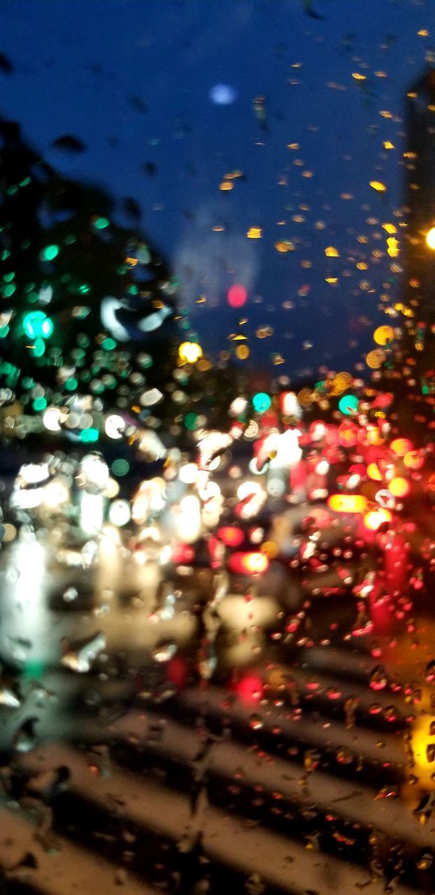 DEFOCUSED IMAGE OF CAR ON ILLUMINATED STREET AT NIGHT