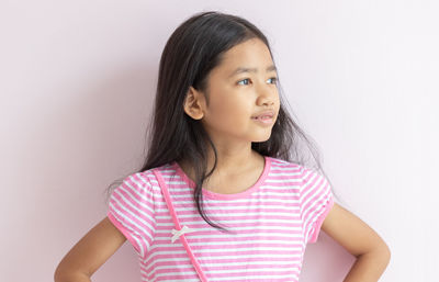 Portrait of happy girl standing against pink wall