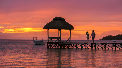 Silhouette pier over sea against sky during sunset