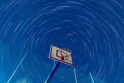 Low angle view of basketball hoop against star trails