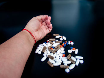 Cropped hand holding medicines over black background