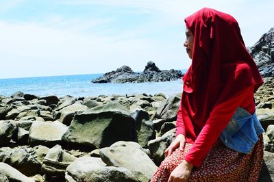 Young woman looking at sea against sky