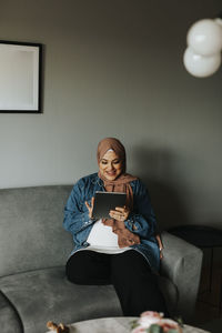 Woman on sofa using digital tablet