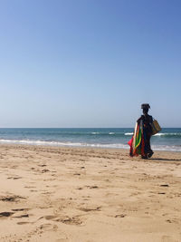Rear view of person on beach against clear sky