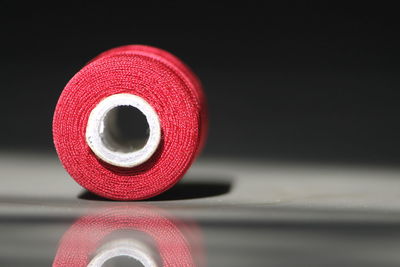 Close-up of red thread rolled up on glass table