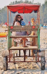 Portrait of woman sitting on chair at beach