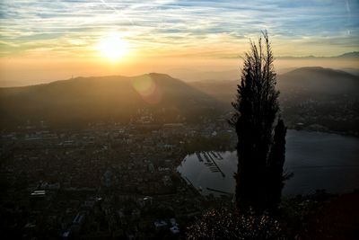 Silhouette tree and cityscape against sky during sunset