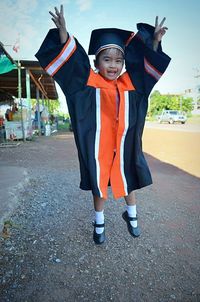 Full length portrait of girl wearing graduation gown jumping