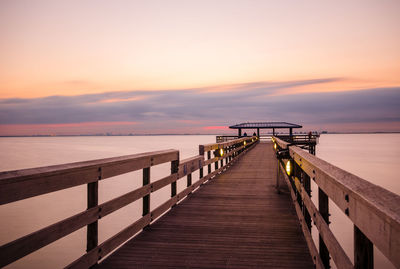 Pier over sea against sky during sunset