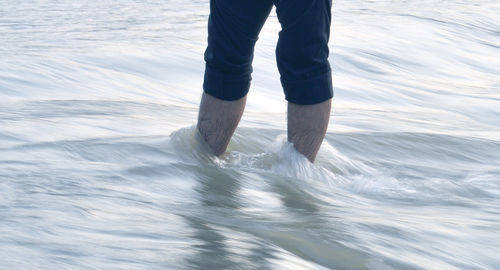 Low section of man standing in sea