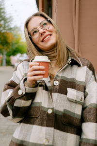 Portrait of smiling young woman drinking coffee