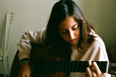 Young woman playing guitar at home